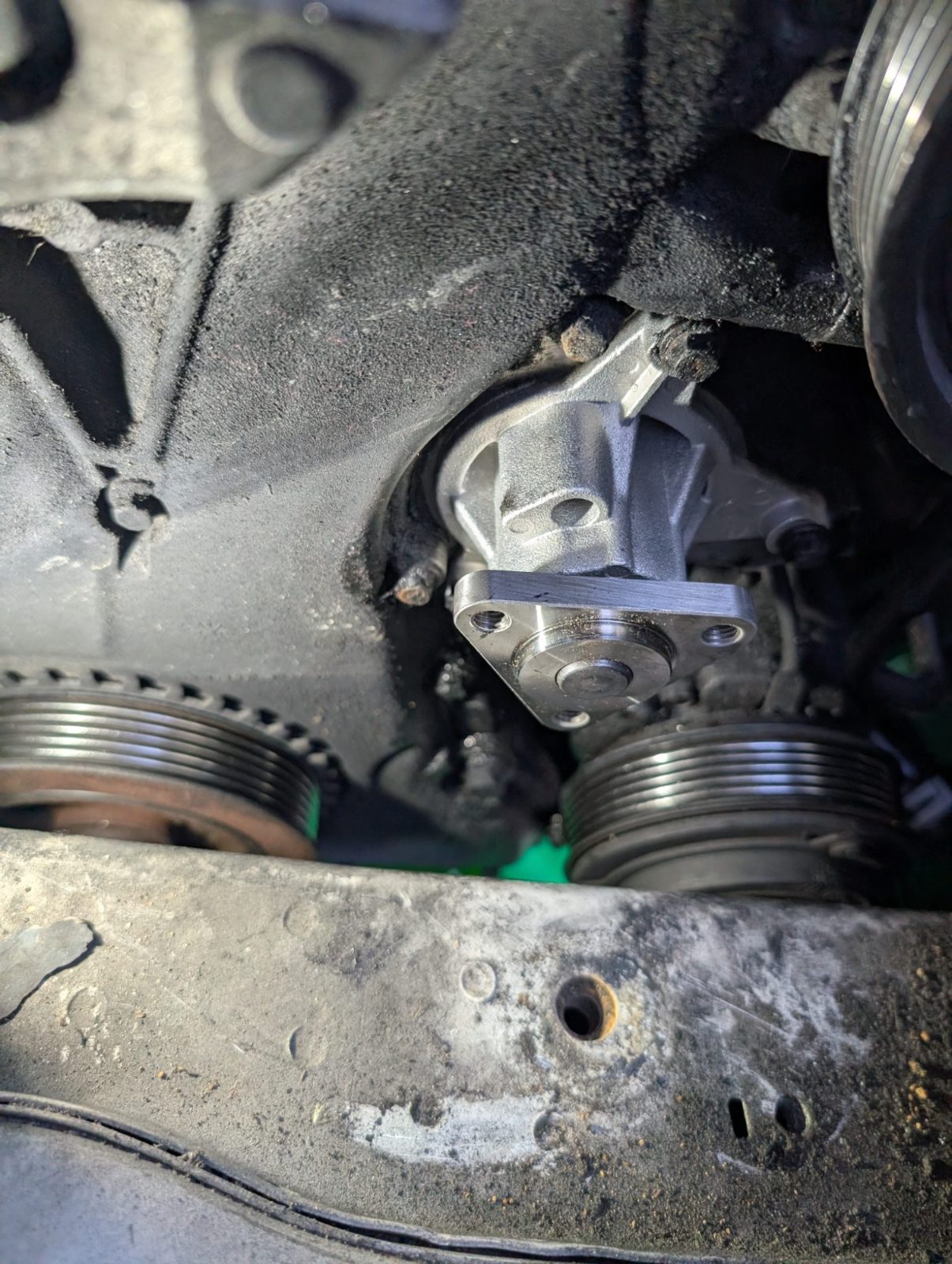 Close view of a new water pump mounted on an engine beside the belt pulleys