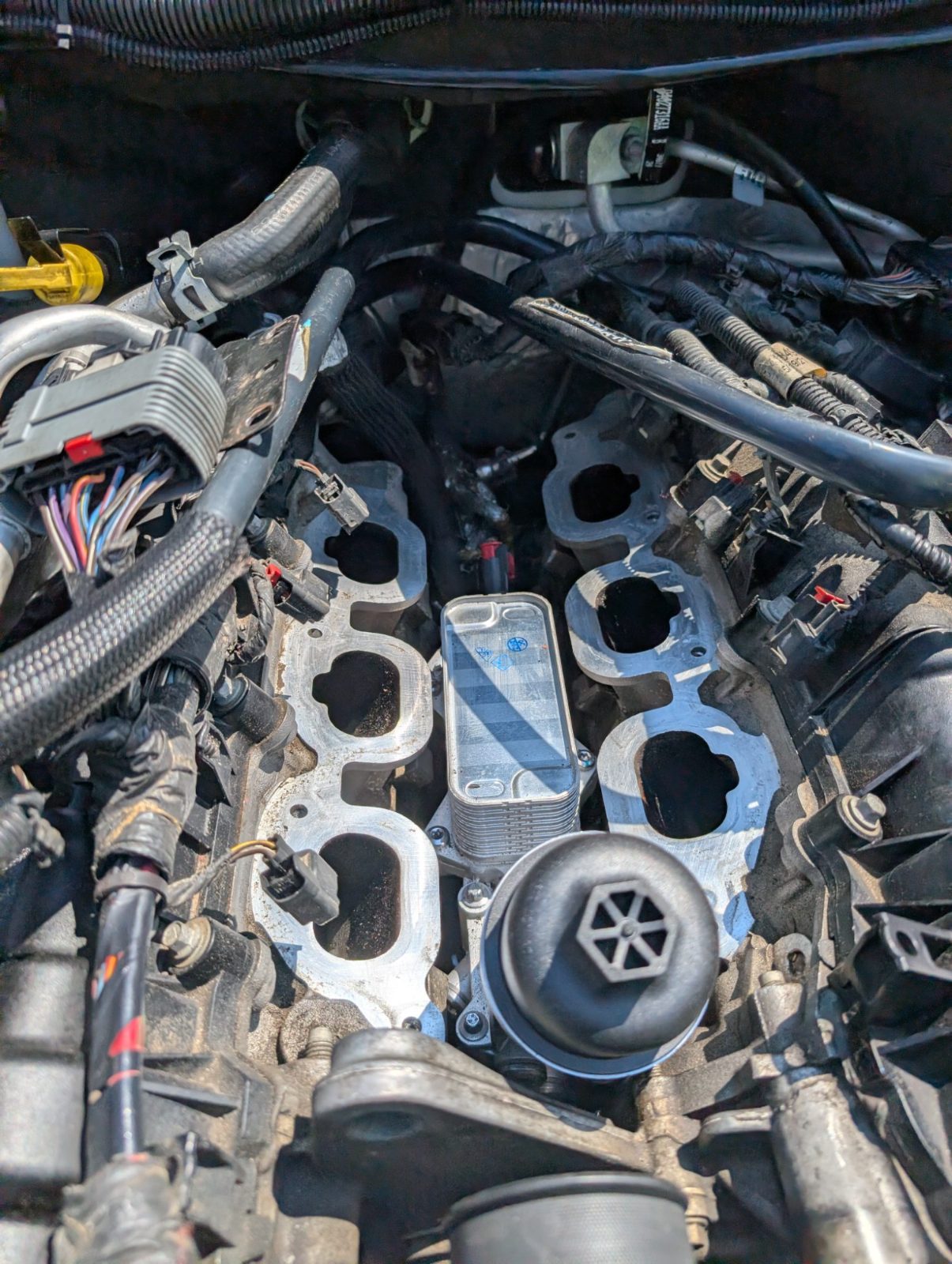Engine bay with the intake removed, exposing ports, wiring and the oil filter housing